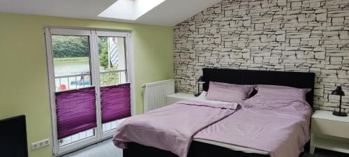 um quarto com uma parede de tijolos e uma cama com lençóis roxos em Ferienhaus Hafen 17 em Hörstel