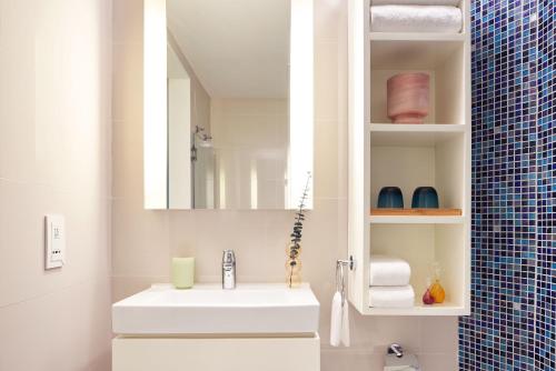 a bathroom with a white sink and a mirror at Ying'nFlo, Wesley Admiralty, Hong Kong in Hong Kong