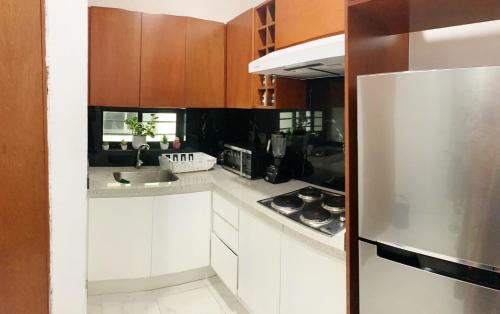 La cuisine est équipée de placards blancs et d'un réfrigérateur en acier inoxydable. dans l'établissement Departamento Cardones - 5 Min Zona Dorada - 6 Personas Alberca Compartida, à Mazatlán
