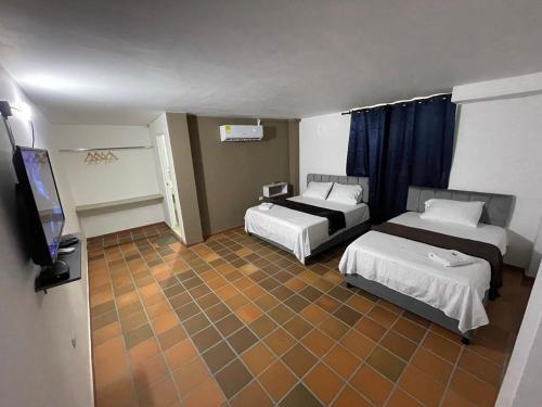 a room with two beds and a flat screen tv at Hotel Valle Central in Valledupar