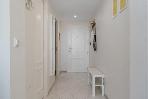 un pasillo con una puerta blanca y un banco pequeño en Miraflores Apartments by the Beach Costa Del Sol, en Mijas Costa