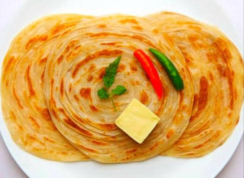 a stack of pancakes on a plate with cheese and peppers at Taj Mahal Residency Muzaffarabad in Muzaffarabad