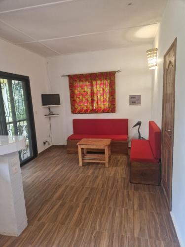 un soggiorno con divano rosso e tavolo di La Cazasamba a Cap Skirring