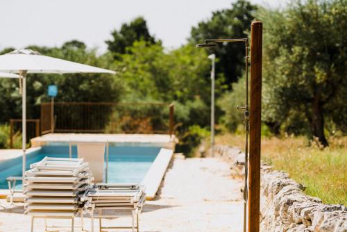 a group of chairs and an umbrella next to a pool at Masseria Soluco in Monopoli