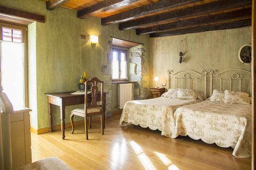 a bedroom with two beds and a table and a desk at Casa rural Txikirrin III - Selva de Irati in Villanueva de Aézcoa