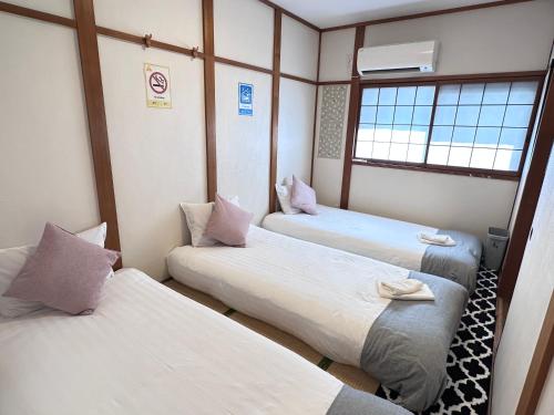 a room with three beds and a window at 旅タイム・大今里南 in Osaka
