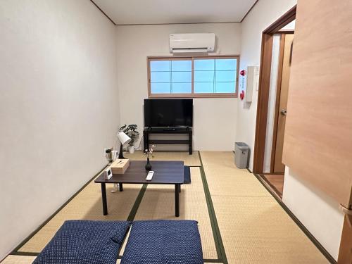 a living room with a table and a tv at 旅タイム・大今里南 in Osaka