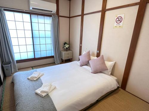a bedroom with a large bed with two towels on it at 旅タイム・大今里南 in Osaka