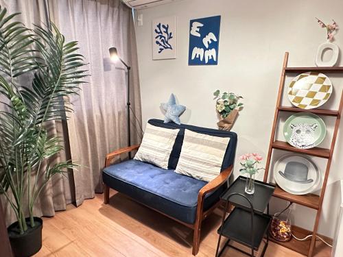 a living room with a blue chair and plants at 旅タイム・大今里南 in Osaka