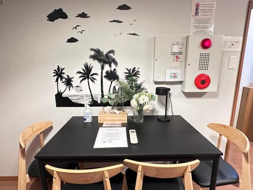 a black table with chairs and palm trees on a wall at 旅タイム・大今里南 in Osaka