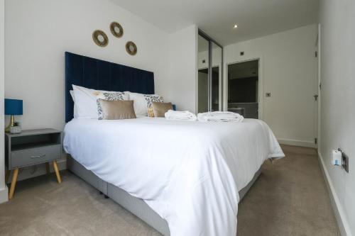 a bedroom with a large white bed with a blue headboard at Brand New 2 bedroom apartment Centre of Solihull in Solihull