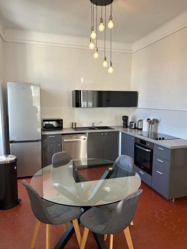 une cuisine avec une table en verre et deux chaises dans l'établissement Typique 3 fenêtres marseillais, à Marseille