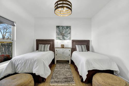 2 Betten in einem weißen Zimmer mit Fenster in der Unterkunft The Homestead Carriage House in Fredericksburg