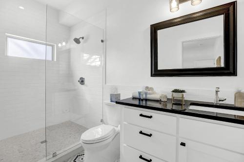 ein weißes Bad mit einem WC und einem Spiegel in der Unterkunft The Homestead Carriage House in Fredericksburg