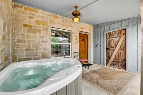 eine Badewanne in einem Zimmer mit einer Steinmauer in der Unterkunft Romantic Oasis with Hot Tub Near Fred and Wineries! in Fredericksburg