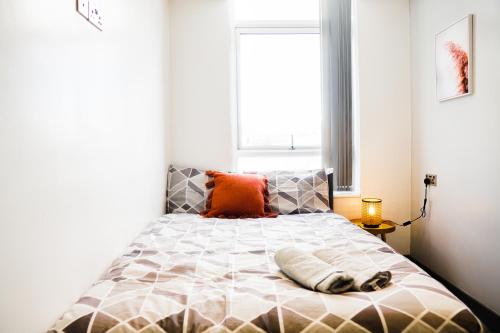 a bedroom with a bed with an orange pillow on it at Cozy Retreat in the Heart of Liverpool in Liverpool