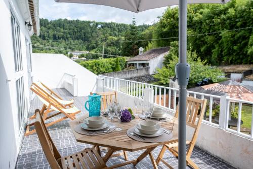 a wooden table on a balcony with an umbrella at Furnas Millhouse in Furnas