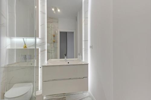 a white bathroom with a sink and a toilet at WAVE APARTMENTS WHITE PEARL IN GDANSK in Gdańsk