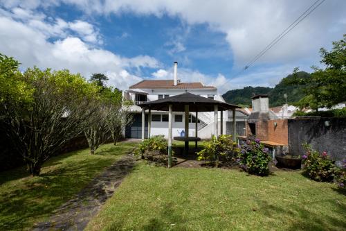 a white house with an umbrella in a yard at Furnas Millhouse in Furnas