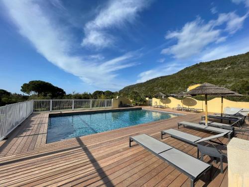- une piscine sur une terrasse en bois avec des chaises et des parasols dans l'établissement CASA PALOMBAGGIA - Piscine Chauffée, à Porto-Vecchio