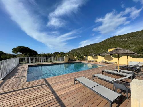- une piscine sur une terrasse en bois avec des chaises et des parasols dans l'établissement CASA PALOMBAGGIA - Piscine Chauffée, à Porto-Vecchio