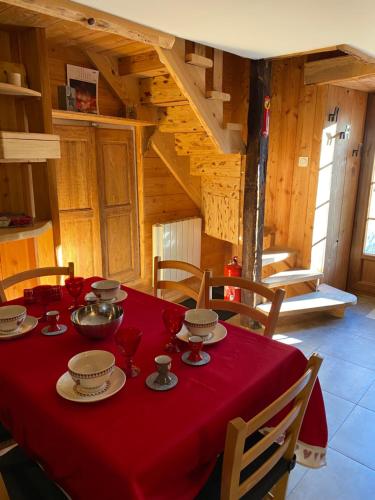 une table avec un tissu de table rouge en haut dans l'établissement BEAU CHALET DE MONTAGNE SERRE CHEVALIER AU PIED DES PISTES PLEIN SUD, à La Salle Les Alpes