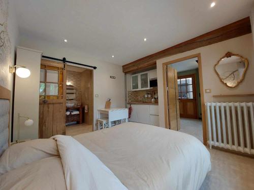 a bedroom with a large white bed and a kitchen at Studiolo des Sources in Charmont-sous-Barbuise