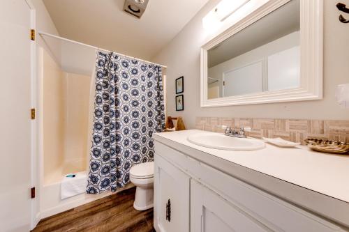 ein Badezimmer mit einem Waschbecken, einem WC und einem Spiegel in der Unterkunft Seashell Beach House in Seaside