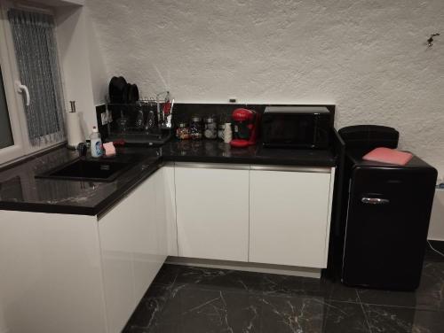 una pequeña cocina con nevera negra y fregadero en La suite Miroir, Love Room, en Bouc-Bel-Air