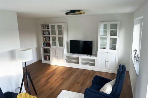 a living room with a television and white cabinets at Residenz an der Ostsee in Scharbeutz