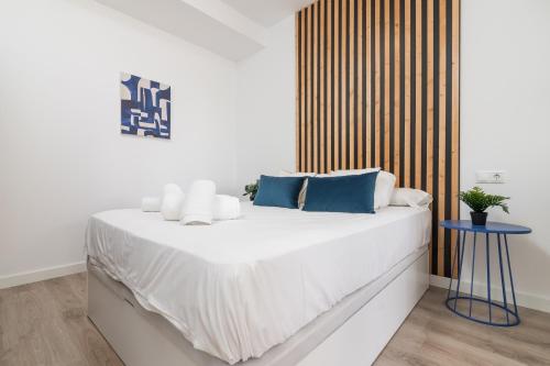 un letto bianco con cuscini blu e un tavolo blu di Suite Homes Hesperides garden beach a Málaga