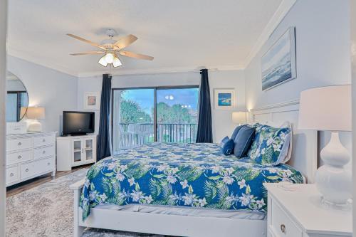 a bedroom with a bed and a tv and a window at Modern oceanfront condo with two pools & private washer/dryer in Saint Augustine