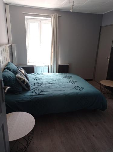 ein Schlafzimmer mit einem Bett mit einer blauen Decke und einem Fenster in der Unterkunft Le café des vacances in Pierre