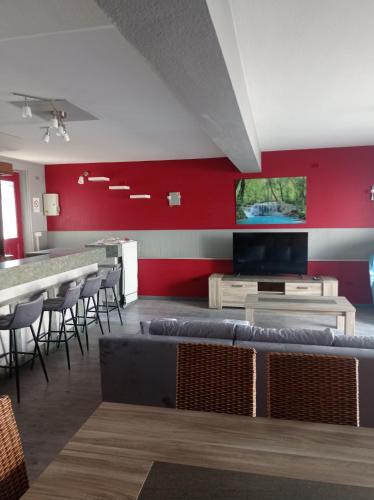 Zimmer mit einer roten Wand mit Stühlen und einem TV in der Unterkunft Le café des vacances in Pierre