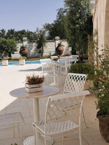 a patio with white chairs and a table and a table at B&B Le Torri in Santeramo in Colle