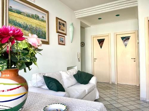 een woonkamer met een witte bank en een vaas met bloemen bij Lulù Holiday House in Vietri