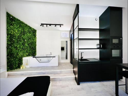 Suite in the City - Standing Hyper-centre JACUZZI CLIM WIFI في مونبلييه: حمام مع حوض استحمام وجدار أخضر