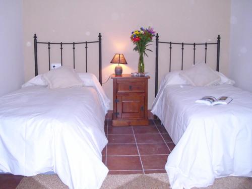 a bedroom with two beds and a table with a vase of flowers at Apartamento San Anton in La Iruela