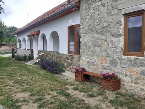 una casa de piedra con un banco delante en Menedék, Silica - Szilice, en Silica