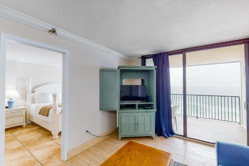 a bedroom with a bed and a tv and a balcony at Emerald Surf 502 in Navarre