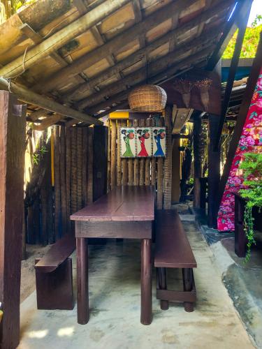 a wooden table and bench under a wooden roof at Pousada Raiz Forte in Caraíva