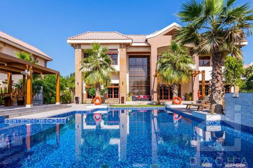 a swimming pool in front of a house with palm trees at آلمعترض in Al Ain