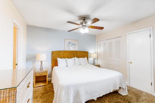 Island Sands 306 في شاطئ فورت والتون: غرفة نوم بسرير أبيض ومروحة سقف