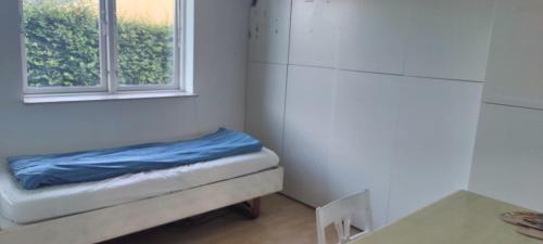 a small room with a bed and a window at Værelse med seng og fælles arealer in Skovlunde