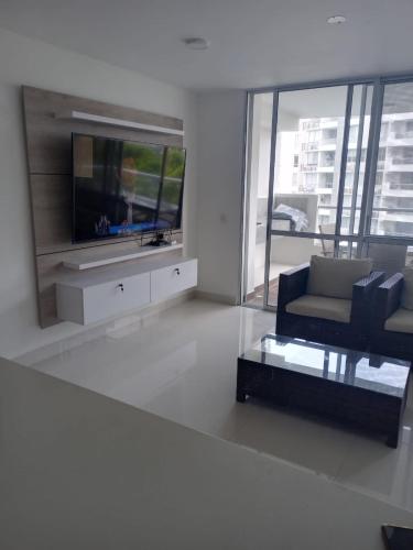 a living room with a couch and a tv at Espectacular apartamento en Condominio con BBQ in Ricaurte