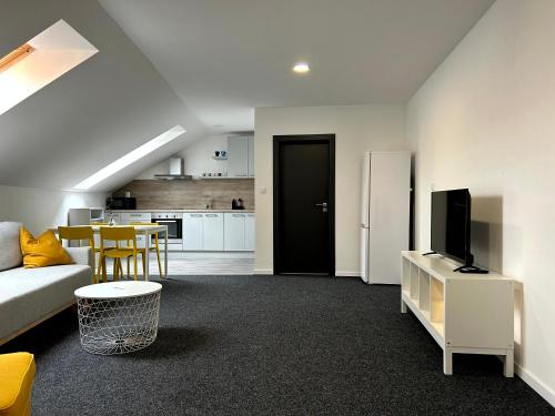 a living room with a couch and a tv and a kitchen at BREZA HOUSE apartments in Zlín