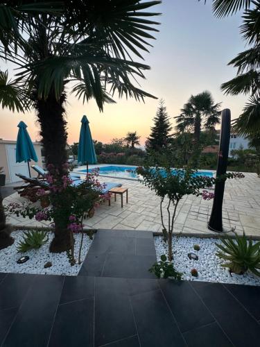 a pool with a table and umbrellas and plants at Holiday House Serenity in Malinska