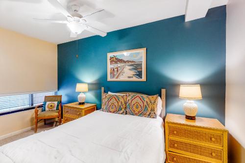 a bedroom with a white bed and a blue wall at Palm Beach Club 2-225 in Pensacola Beach