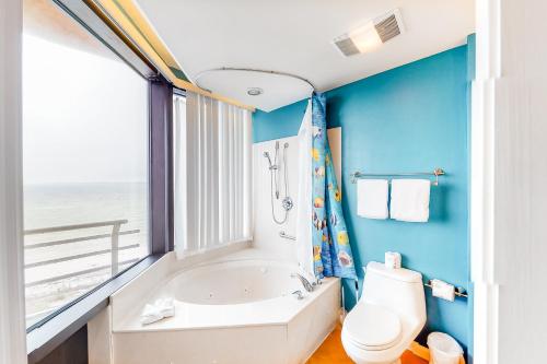 a bathroom with a tub and a toilet and a window at Palm Beach Club 2-225 in Pensacola Beach
