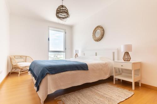 a white bedroom with a bed and a chair and a window at Belavista Oceanside in Ribeira Grande